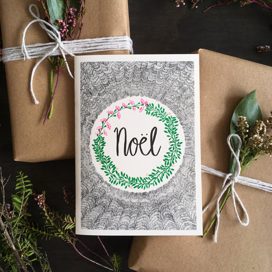 Greeting card with Noel written at the center surrounded by a wreath