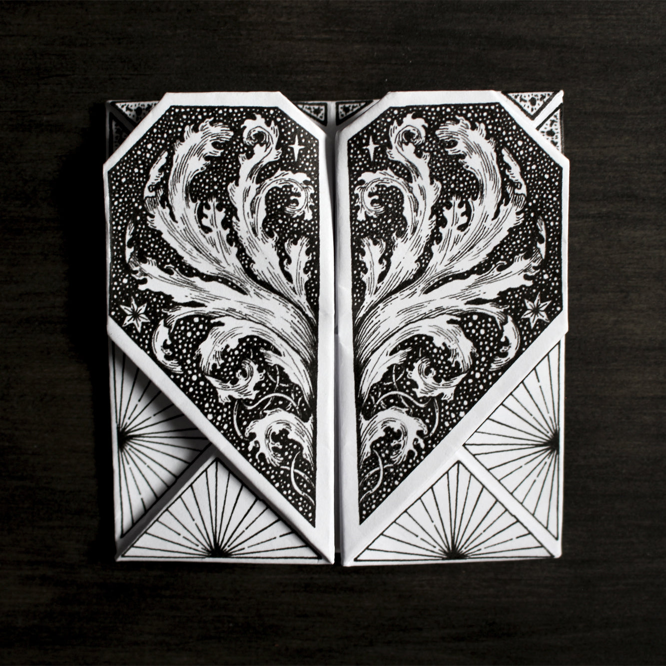 Origami Secret Hearts printed on white paper placed on dark wood backrgound. 