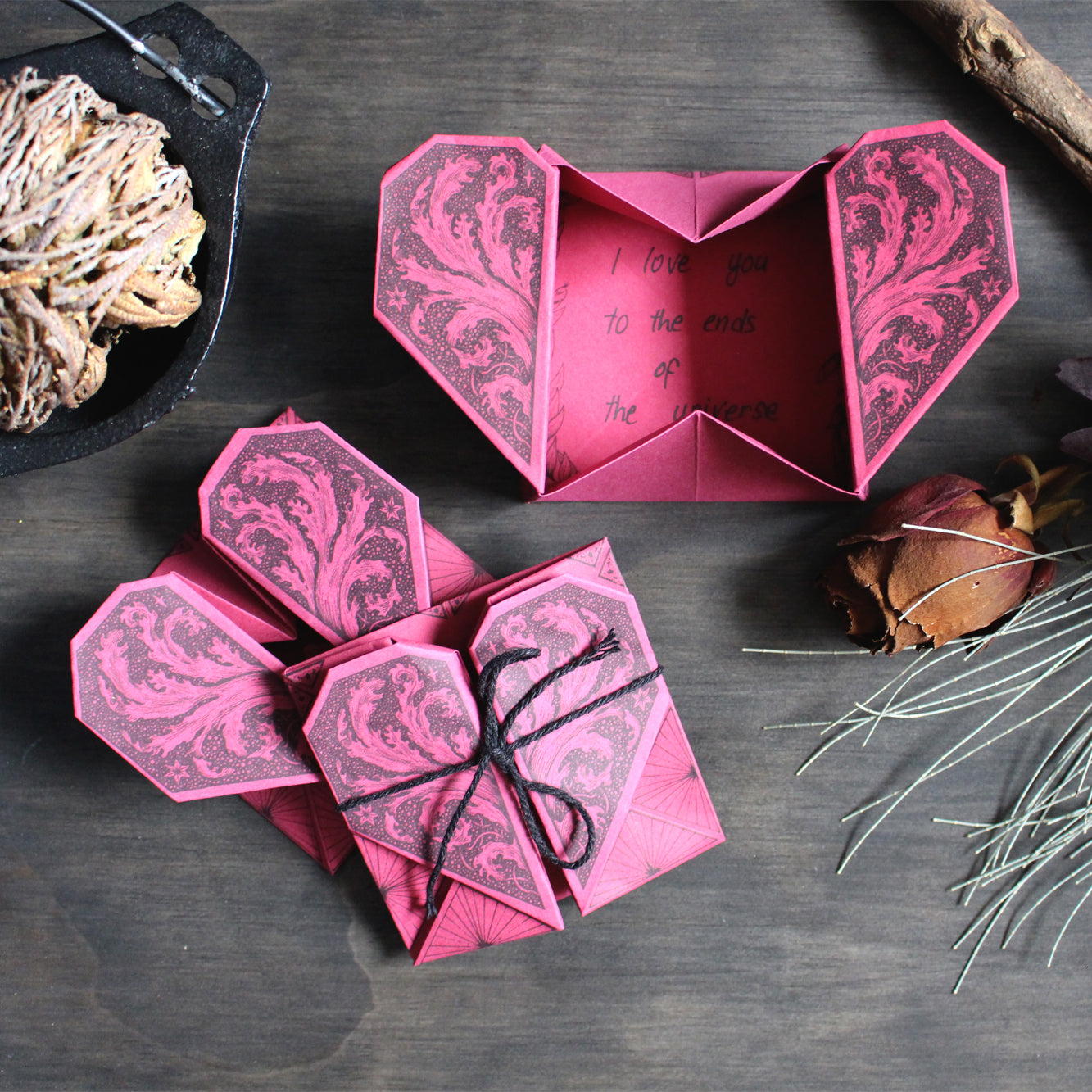 Origami Secret Hearts printed on red paper placed on dark wood backrgound.