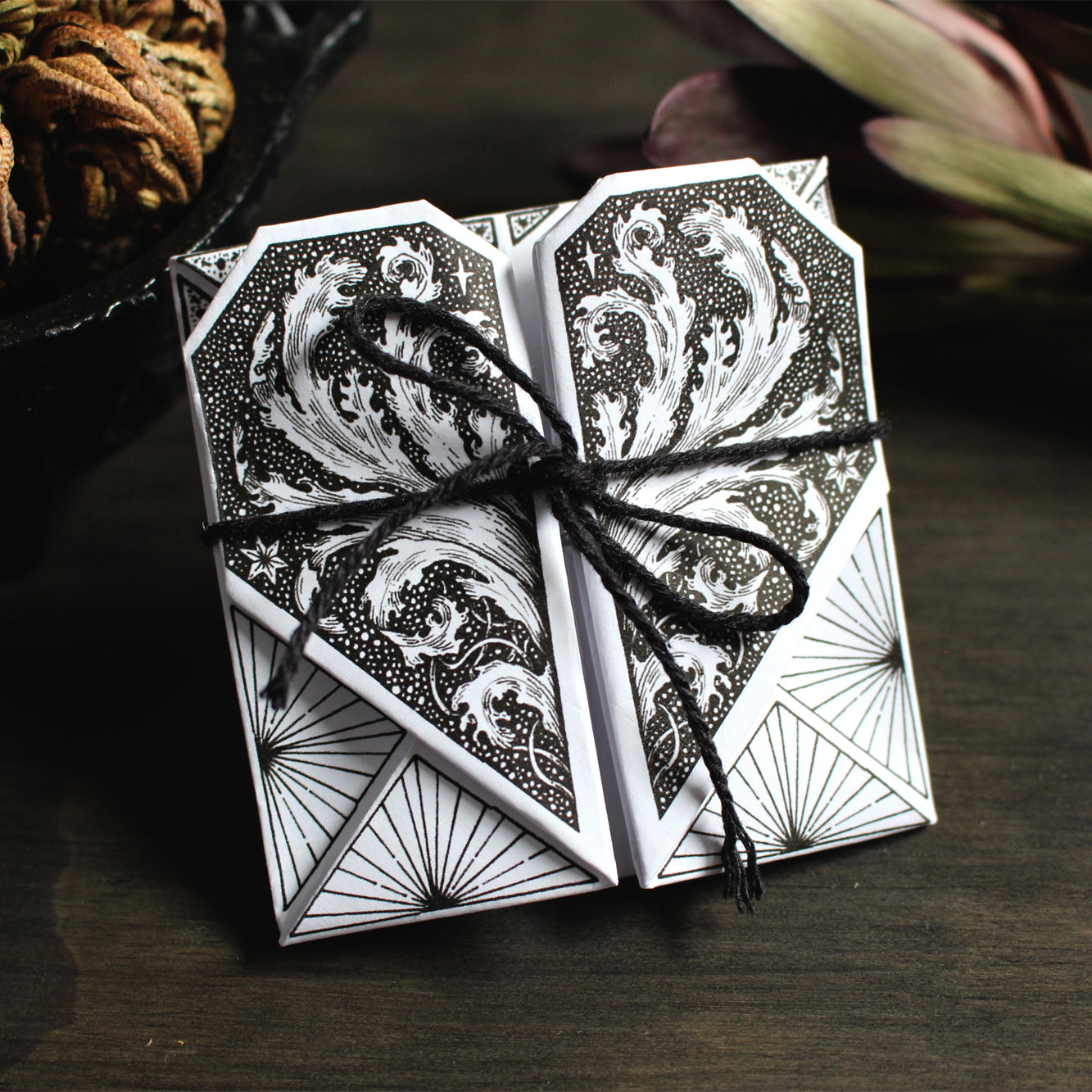 Origami pocket hearts printed on white paper tied by a string.