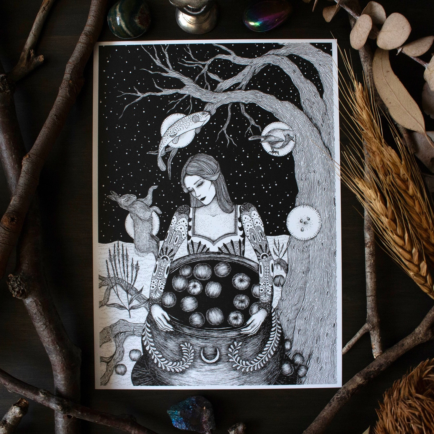 Illustration of a woman with a cauldron of apples against a starry night sky, surrounded by nature elements.